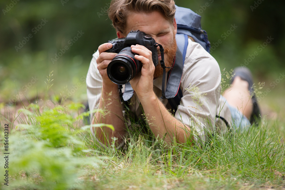 the photographer lies on the grass with a camera the photographer lies on the grass with a camera