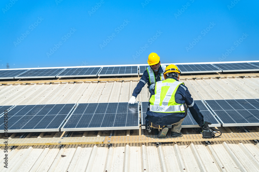Worker Technicians are working to construct solar panels system on roof with sky and clound on background. Installing solar photovoltaic panel system. Renewable clean energy technology concept. Worker Technicians are working to construct solar panels system on roof with sky and clound on background. Installing solar photovoltaic panel system. Renewable clean energy technology concept.
