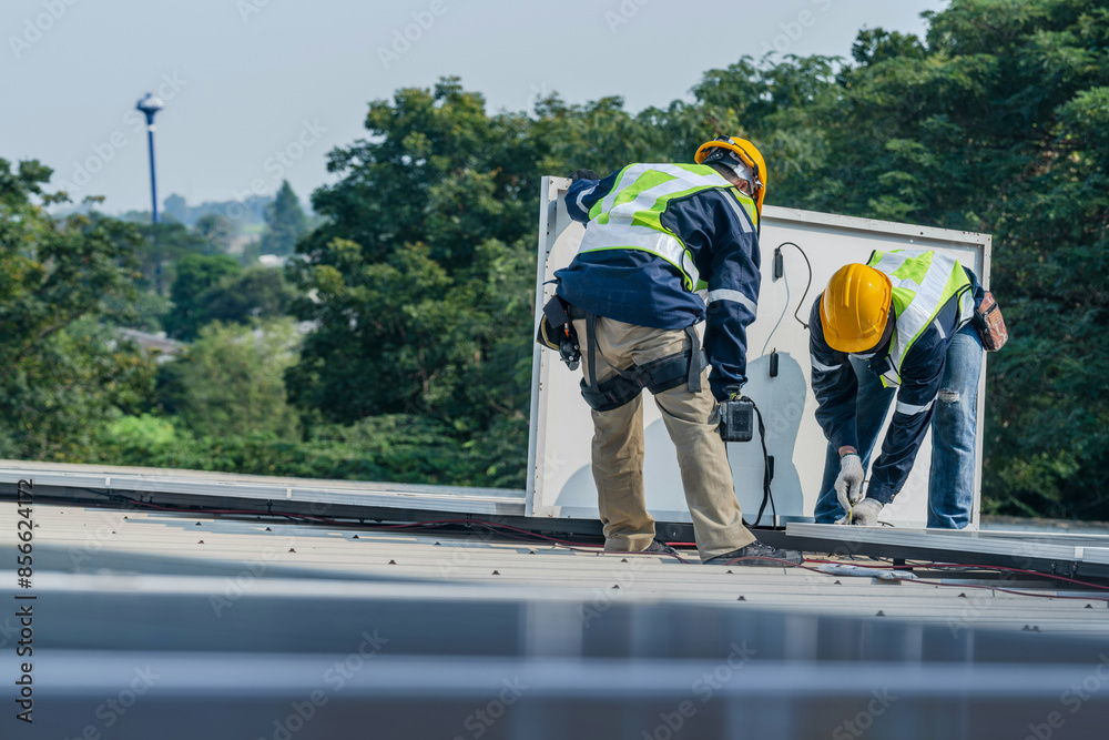 Worker Technicians are working to construct solar panels system on roof. Installing solar photovoltaic panel system. Men technicians carrying photovoltaic solar modules on roof. Worker Technicians are working to construct solar panels system on roof. Installing solar photovoltaic panel system. Men technicians carrying photovoltaic solar modules on roof.