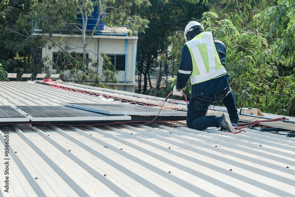 Worker Technicians are working to construct solar panels system on roof. Installing solar photovoltaic panel system. Men technicians carrying photovoltaic solar modules on roof.