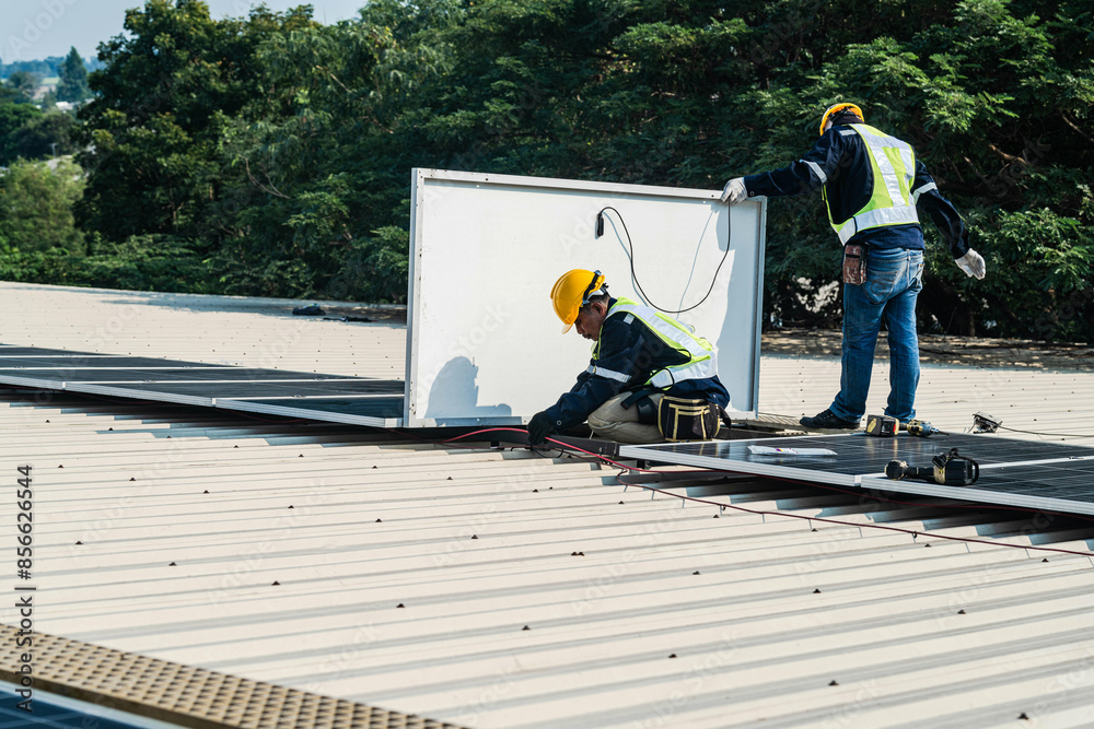 Worker Technicians are working to construct solar panels system on roof. Installing solar photovoltaic panel system. Men technicians carrying photovoltaic solar modules on roof. Worker Technicians are working to construct solar panels system on roof. Installing solar photovoltaic panel system. Men technicians carrying photovoltaic solar modules on roof.
