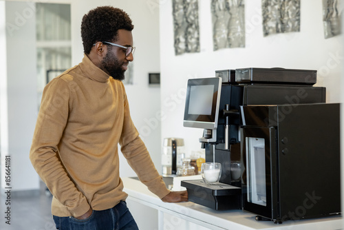 Obraz na plátně Man office worker using modern coffee machine making coffee in office