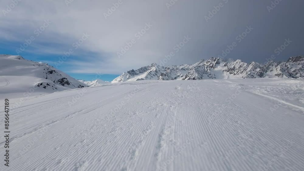 Drone shot over a snow covered slope capturing the majestic alpine landscape on a cloudy day during winter season, Switzerland. Amazing mountain background of the swiss alps, white landscape, 4K