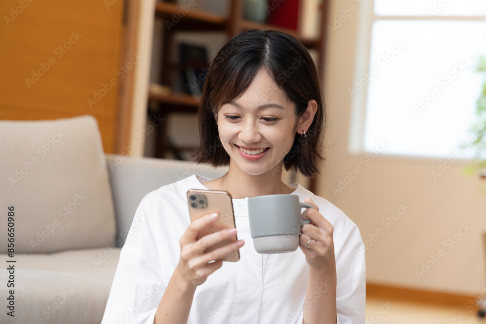居間でスマートフォンを触る30代女性