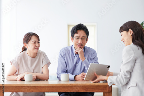 スーツを着てタブレット端末を持つ女性と夫婦 photo