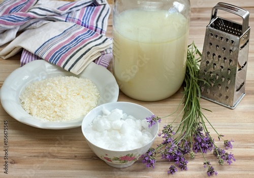 Homemade laundry detergent made from grated soap, crystalline sodium, essential oil and water. Lavender herb and crystalline sodium in front, ready detergent in the bottle at back.