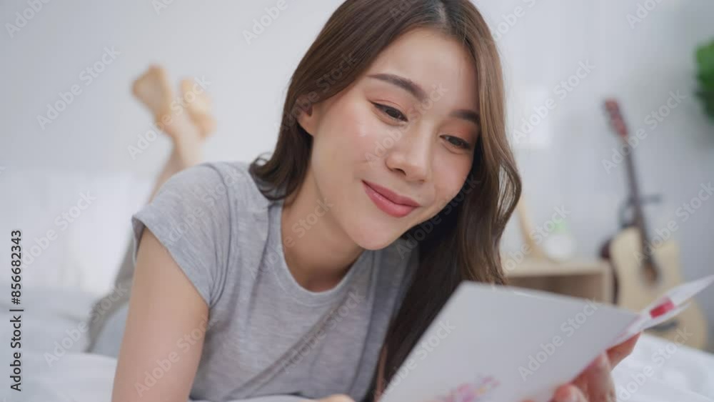 Asian young beautiful woman reading a card in bedroom at home. Asian young beautiful woman reading a card in bedroom at home.