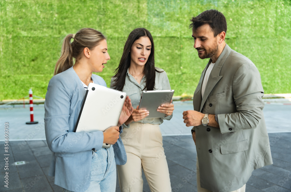Group of successful young business people, leaders in marketing and motivation, stand in front of office building and consult before a meeting with employees. HR communication in companies concept Group of successful young business people, leaders in marketing and motivation, stand in front of office building and consult before a meeting with employees. HR communication in companies concept
