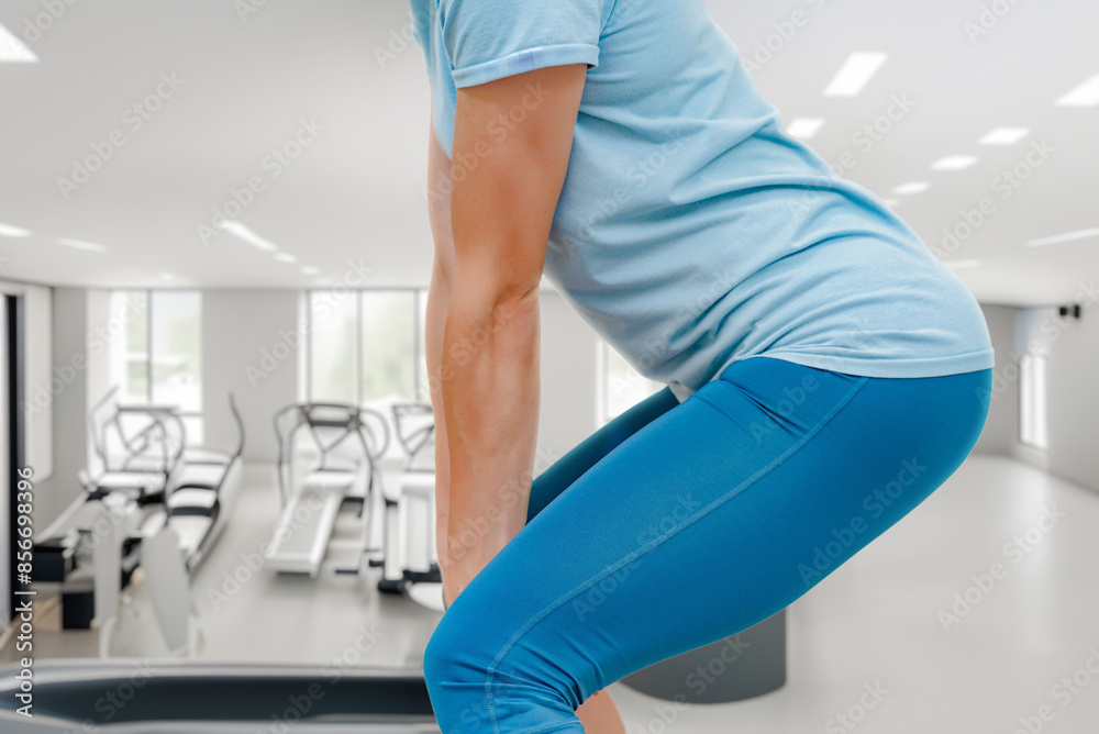 Closeup photo of sporty young woman doing squat. Fitness dedication: a girl commits to solo gym sessions in a modern fitness center Closeup photo of sporty young woman doing squat. Fitness dedication: a girl commits to solo gym sessions in a modern fitness center