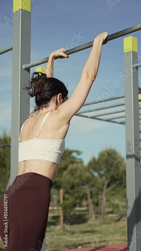 Frustrated Young Woman Failing to Perform Muscle-Up. Young woman in her twenties struggles and fails to perform a muscle-up in an outdoor calisthenics park. photo