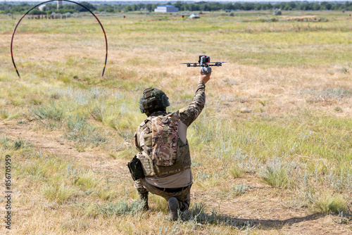 Soldiers launching a combat drone into flight. A soldier uses a drone for reconnaissance during a military operation. A soldier ties a grenade to blow up an enemy with a military drone.