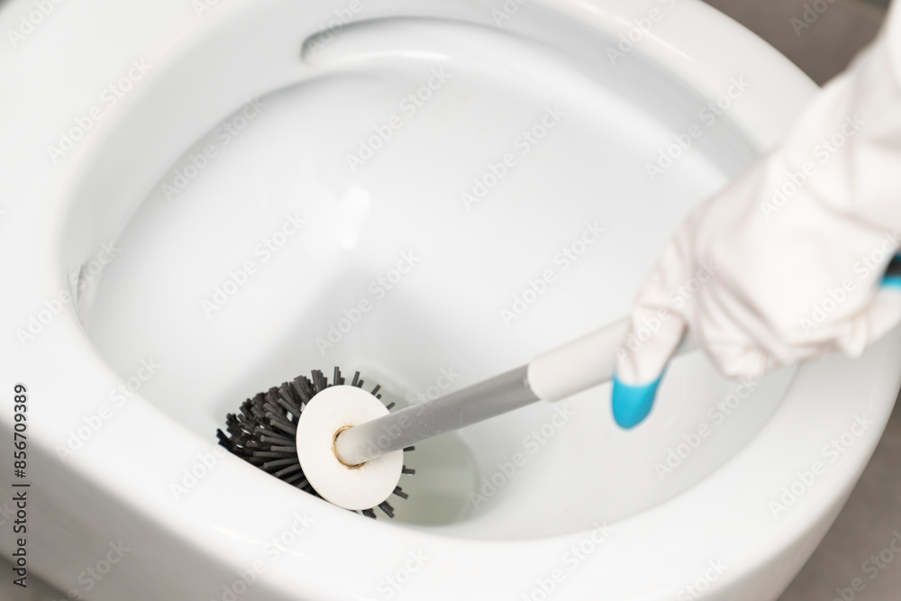 Сlose-up shot of a man in rubber gloves cleaning a toilet using a special cleaning product and a brush Сlose-up shot of a man in rubber gloves cleaning a toilet using a special cleaning product and a brush