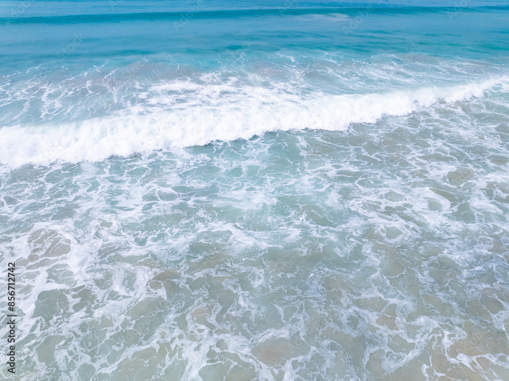 Top view beach with waves crashing on sandy shore,Beautiful waves sea surface in summer seascape background,Amazing beach colorful water background Top view beach with waves crashing on sandy shore,Beautiful waves sea surface in summer seascape background,Amazing beach colorful water background