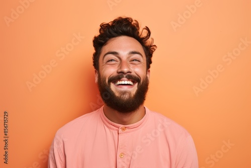 Happy Caucasian man, 26 years old, winking on a pastel salmon background © Hanna Haradzetska
