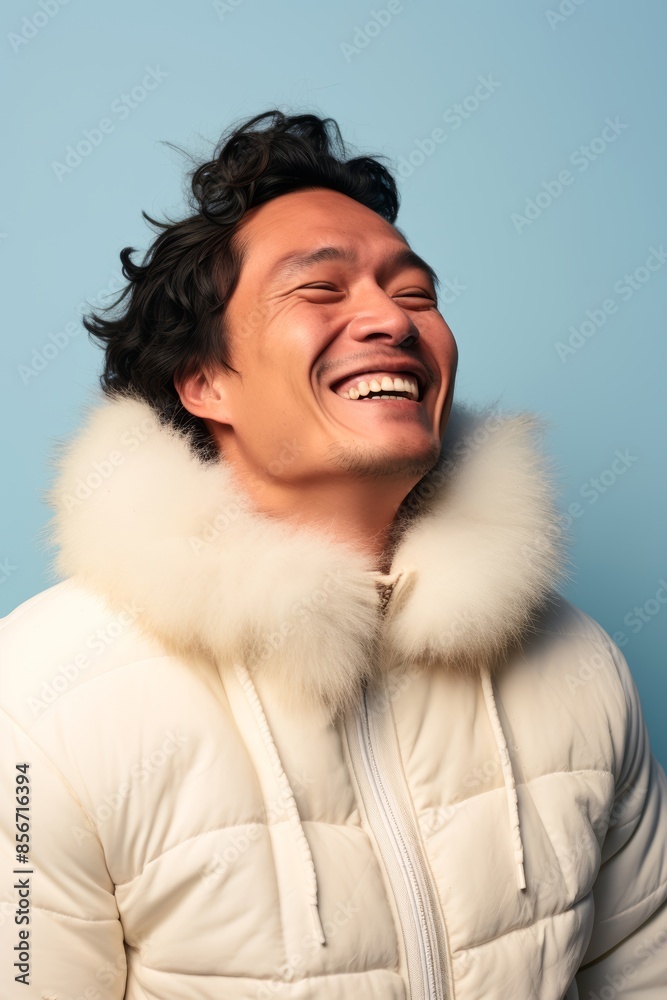 A smiling Inuit man, 32 years old, winking on a pastel sky blue background A smiling Inuit man, 32 years old, winking on a pastel sky blue background