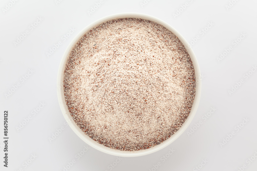 Organic Ragi (Eleusine coracana) or Finger Millet Flour in a white ceramic bowl. Isolated on a grey background. Top View