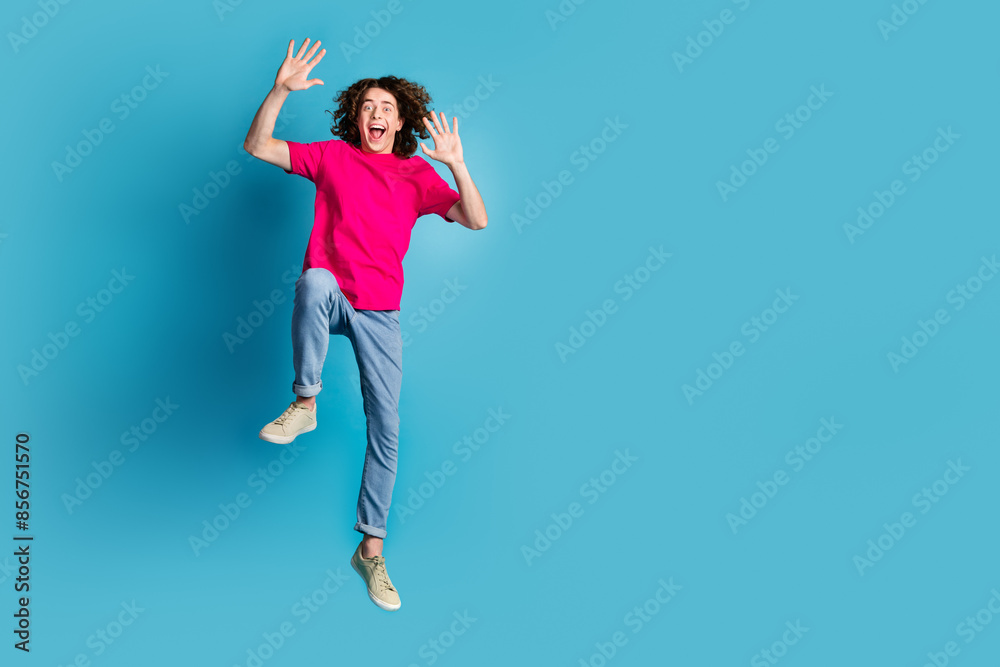 Full size photo of nice young man jump raise hands wear t-shirt isolated on blue color background Full size photo of nice young man jump raise hands wear t-shirt isolated on blue color background