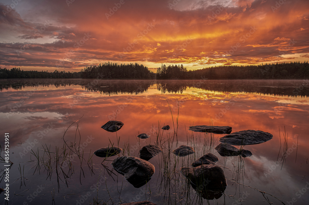 stones in the calm water reflecting the sunrise in a swedish lake