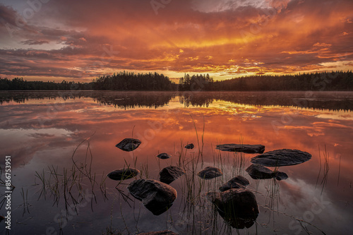 Obraz na płótnie stones in the calm water reflecting the sunrise in a swedish lake w salonie