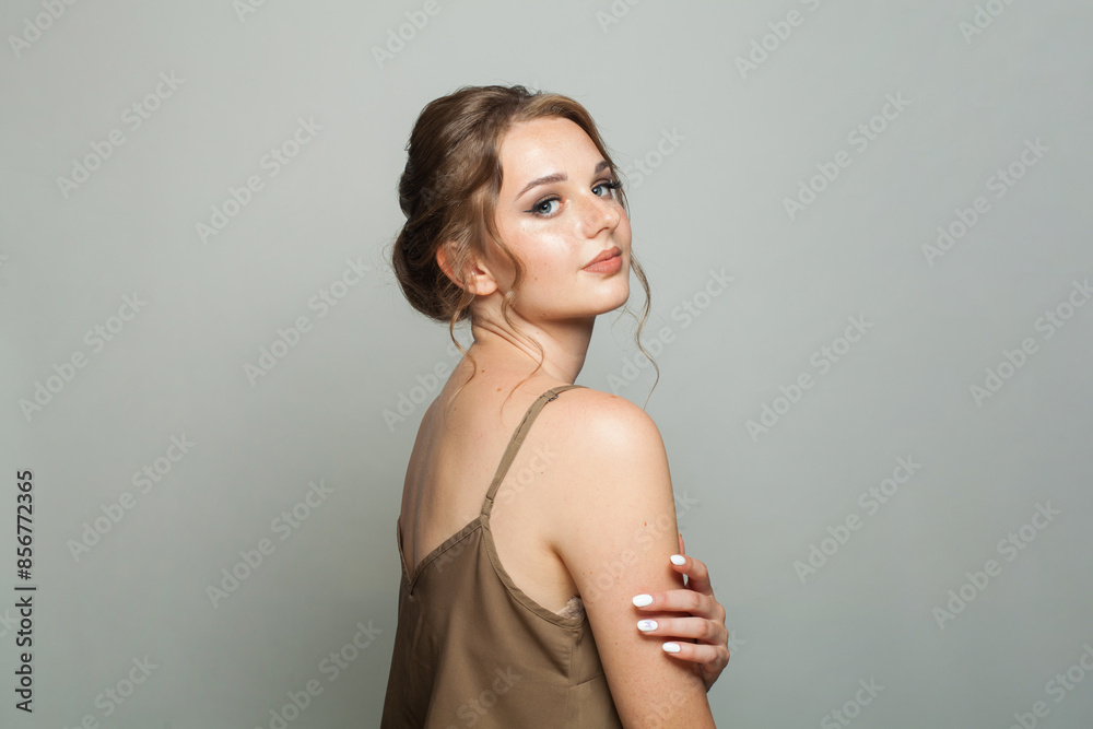 Fototapeta premium Cheerful good-looking woman with updo hairstyle and makeup. Young female model portrait