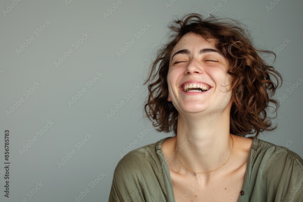Portrait of a cheerful woman in her 30s laughing on blank studio backdrop