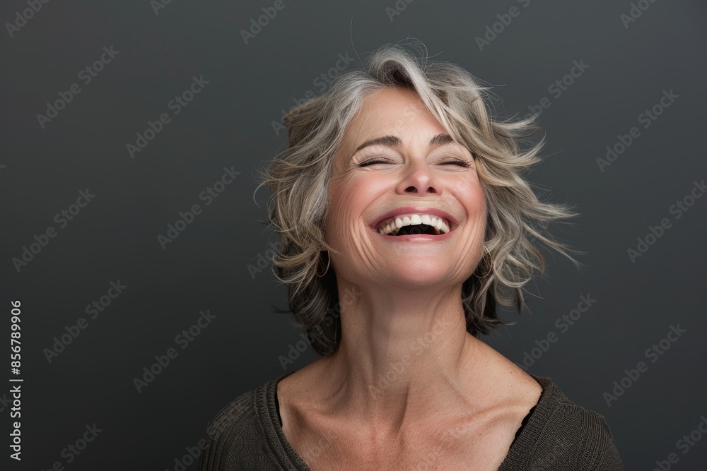 Portrait of a glad caucasian woman in her 50s laughing isolated in blank studio backdrop Portrait of a glad caucasian woman in her 50s laughing isolated in blank studio backdrop