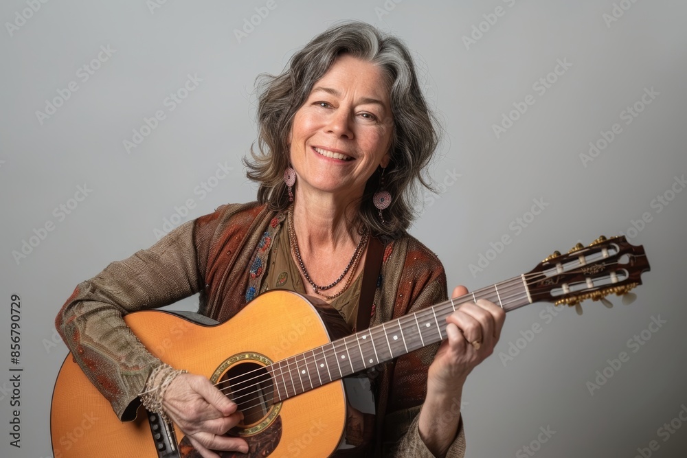 Portrait of a cheerful caucasian woman in her 50s playing the guitar isolated on blank studio backdrop Portrait of a cheerful caucasian woman in her 50s playing the guitar isolated on blank studio backdrop