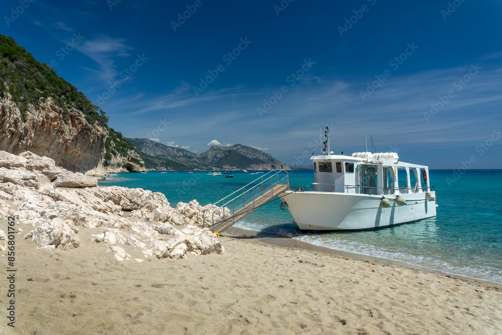 Fototapeta premium Tourism cruise boat at Cala Luna beach and clear transparent blue water in the Gulf of Orosei, Sardinia island, Italy