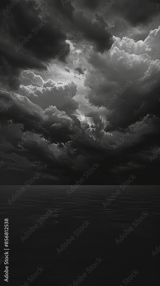 Obraz premium A black and white photograph of a stormy sky over a calm sea at dusk. The clouds are dark and ominous, but the sea is still and peaceful