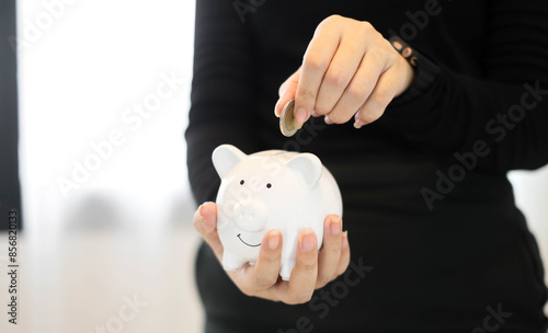 Young woman are putting coins in the piggy bank Saving money with coins Step into a business the growing business for success and saving for retirement