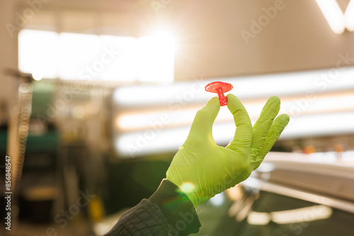 A person with green gloves holds a red pin in their hand who starting to work on damaged car roof of the car