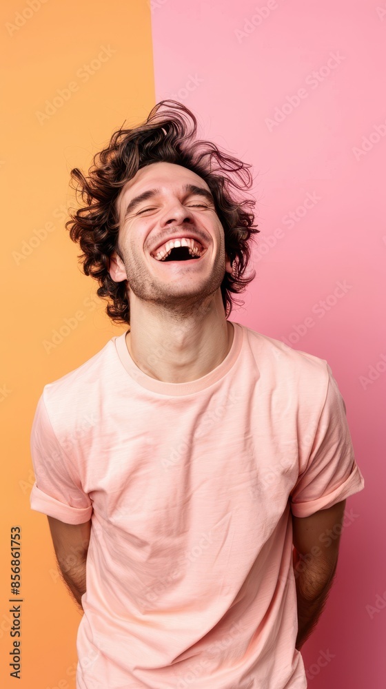 Man with curly brown hair laughing on pink and orange background Man with curly brown hair laughing on pink and orange background