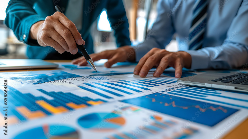 Advertisers analyzing market trends with charts and graphs on a large table, intense discussion, bottom third copy space Advertisers analyzing market trends with charts and graphs on a large table, intense discussion, bottom third copy space