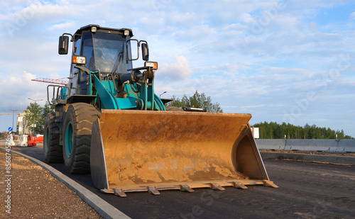 Wheel loader with a bucket on the road construction. Construction site with heavy machinery on road construction. Civil engineering. Heavy machinery for loading and unloading works on roadworks.