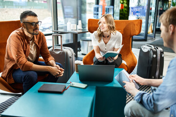 Multicultural colleagues in casual attire gathered around a table with luggage, discussing during a business trip.