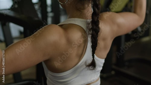 Foman training upper back muscle in gym, close-up of muscles, workout shot. photo