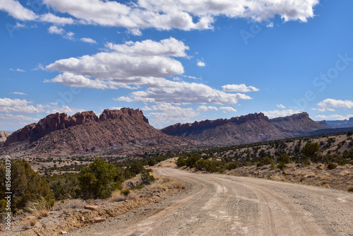 Scenic view of Capitol Reef National Park in Utah featuring the majestic Waterpocket Fold under a blue sky with scattered clouds. The winding dirt road is known as the Burr Trail - USA