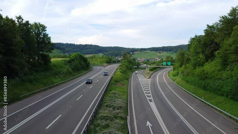 Light traffic on a European motorway or freeway. Above view from an overpass, summer evening, green forest on the sides, real time, no people Light traffic on a European motorway or freeway. Above view from an overpass, summer evening, green forest on the sides, real time, no people