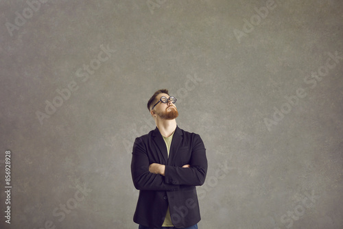 Guy with inflated self-esteem feeling very important. Portrait funny arrogant pretentious overbearing egocentric man in nerdy glasses looking away standing arms crossed against grey studio background