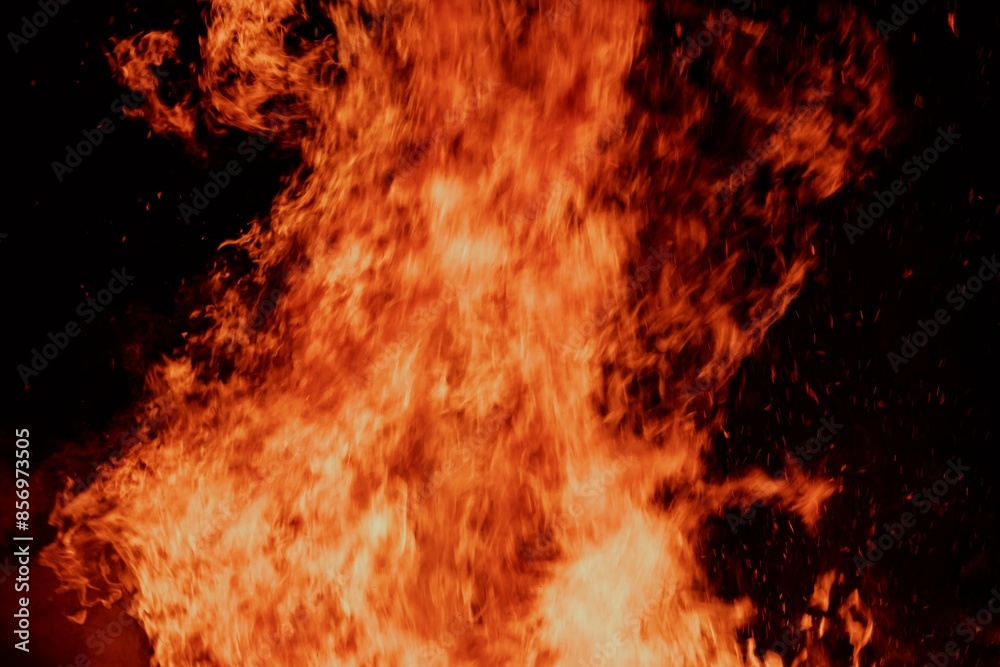 Close-up view of a large fire with intense flames against a dark background. Close-up view of a large fire with intense flames against a dark background.