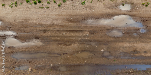 Foto view from above on texture of wet gravel road with puddles after rain
