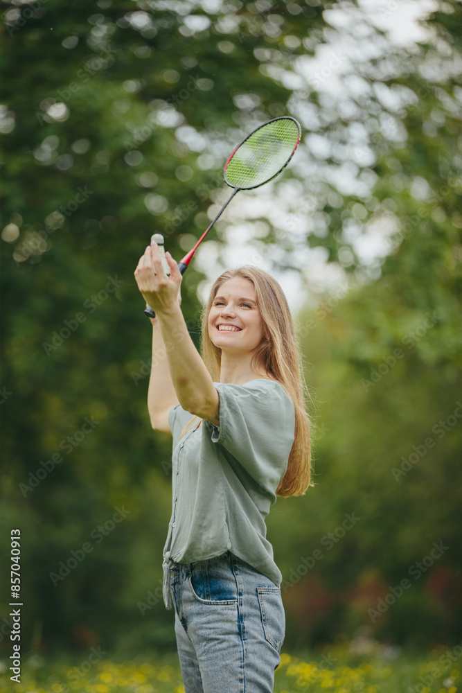 Beautiful young blonde woman posing with a badminton racket and a shuttlecock in the park. Beautiful young blonde woman posing with a badminton racket and a shuttlecock in the park.