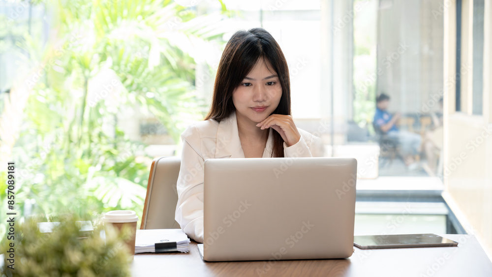 An attractive, thoughtful Asian businesswoman is working remotely from a cafe, using her digital tablet, gazing at the view outside, and thinking about her new ideas. An attractive, thoughtful Asian businesswoman is working remotely from a cafe, using her digital tablet, gazing at the view outside, and thinking about her new ideas.