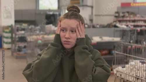 Sad frustrated woman in the grocery store dissatisfied because of high prices. 