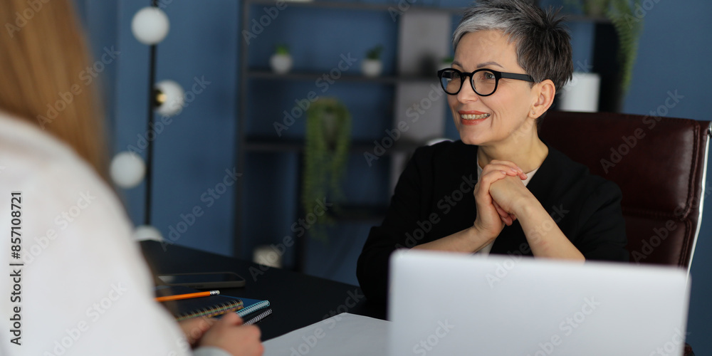 Mature businesswoman in a meeting with a colleague, showcasing teamwork and professional communication. Mature businesswoman in a meeting with a colleague, showcasing teamwork and professional communication.