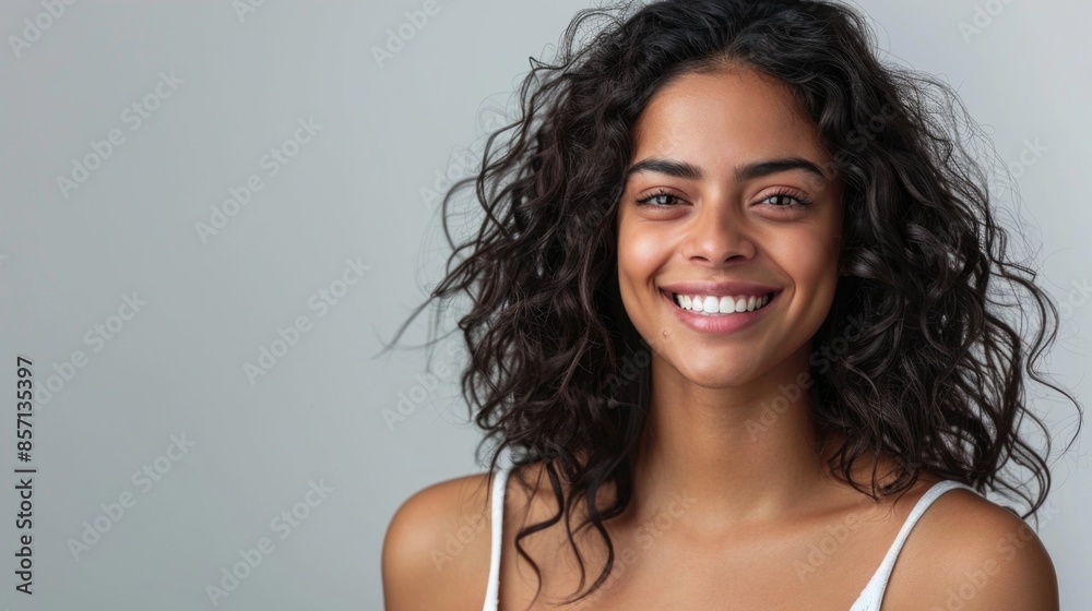 Beautiful woman with dark curly hair smiling on grey background. Beautiful woman with dark curly hair smiling on grey background.