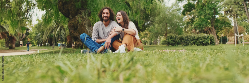 Happy smiling couple talking while sitting on blanket in park Happy smiling couple talking while sitting on blanket in park