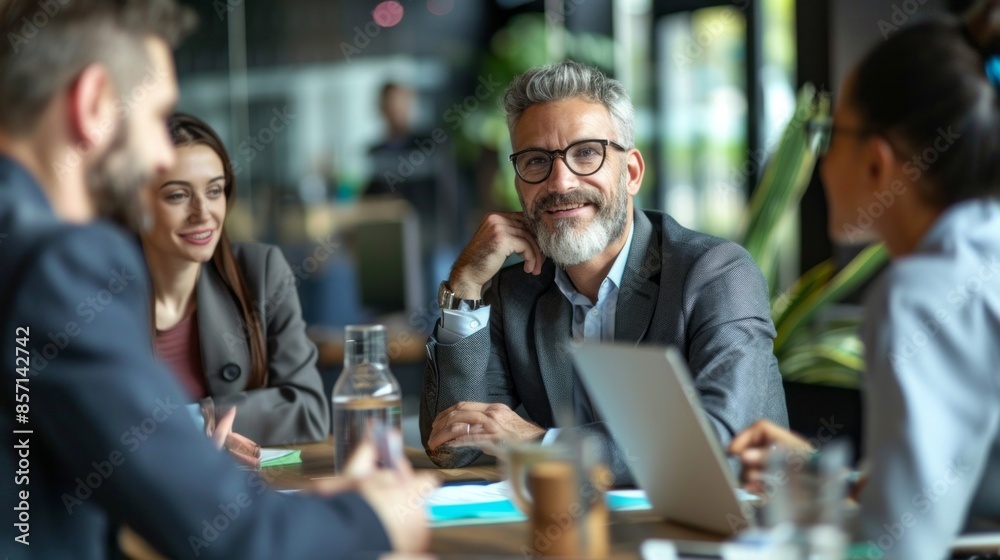 A group of people are sitting around a table in a business setting A group of people are sitting around a table in a business setting