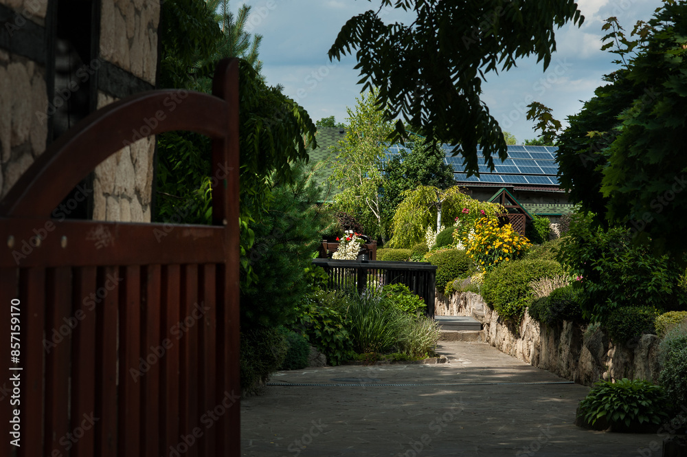 Fototapeta premium entrance to the yard with a beautiful landscape design, cascades of colored bushes and flowers