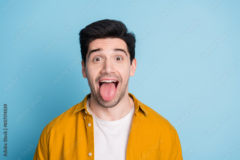 Photo of funky funny guy dressed yellow shirt stick out emtpy space isolated blue color background Photo of funky funny guy dressed yellow shirt stick out emtpy space isolated blue color background